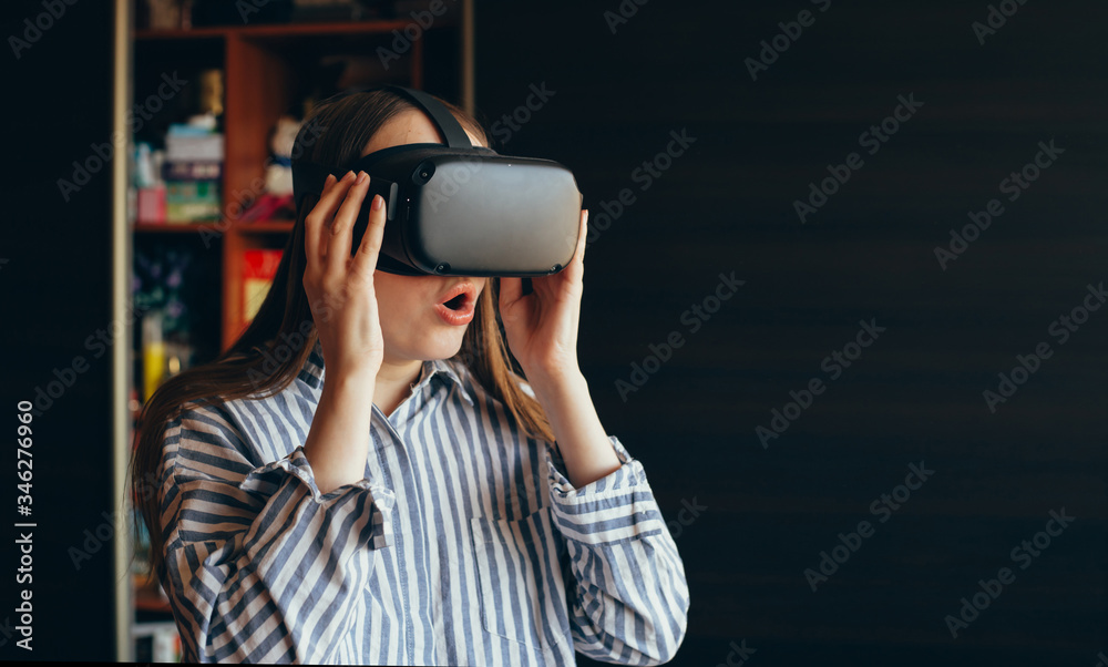 vr glasses. girl in VR glasses on a dark background mmersion in virtual reality, augmented reality glasses. girl holding VR glasses. girl on the background of the office