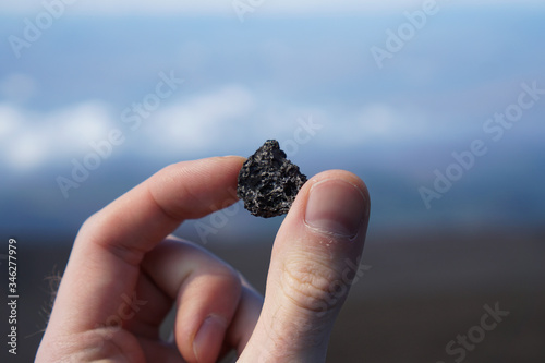 A hand holding a small piece of volcanic rock.