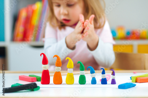 Bild auf Leinwand Girl molding colorful gnomes from childs play clay on the table