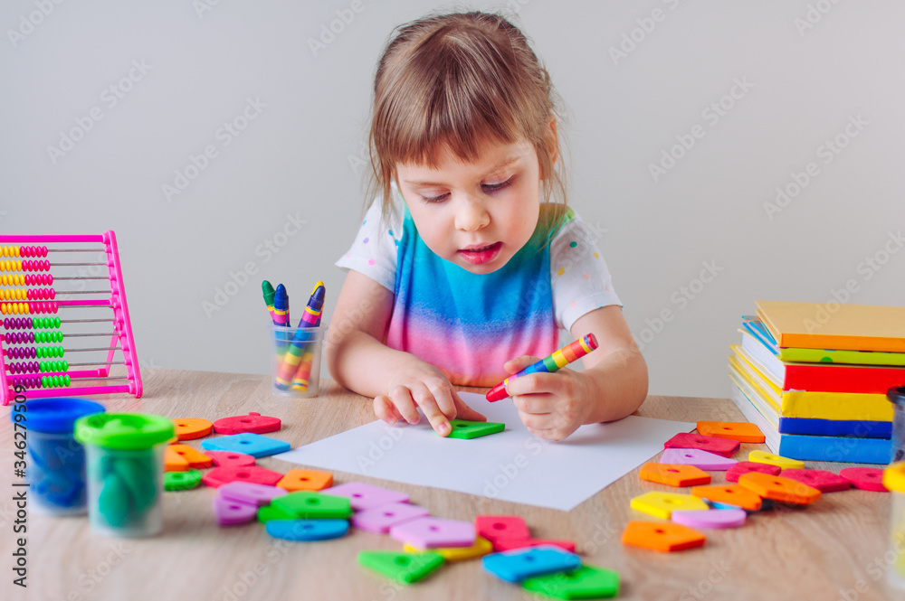 Beautiful little girl drawing with wax crayons and geometrical shapes Beautiful little girl drawing with wax crayons and geometrical shapes