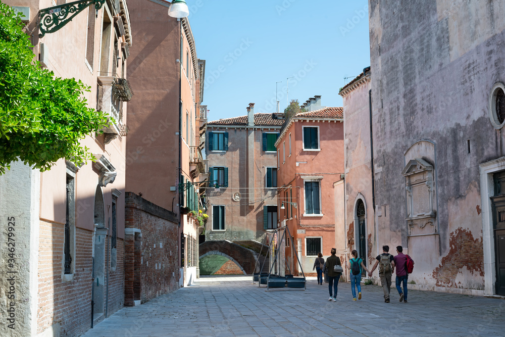 Tourists walking down a beautiful street toward a bridge in Venice. View to bridge Ponte Storto near the Church of San Marcuola, Cannaregio district, Venice, Italy