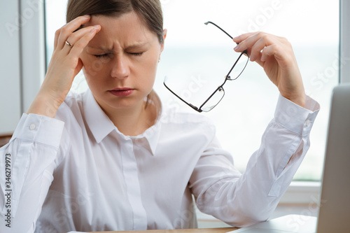 Young woman got headache at work. Finance problems, crisis coming.