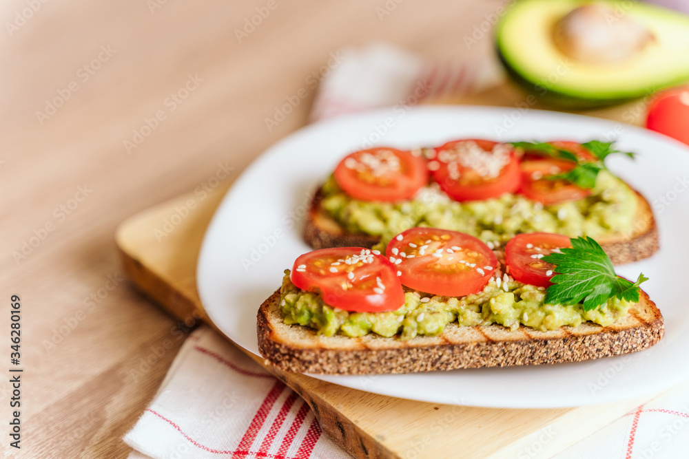 toasted bread with avocado paste and fresh tomato. Avocado mixed with lemon juice is spread on bread. health food concept, vegan, vegetarian toasted bread with avocado paste and fresh tomato. Avocado mixed with lemon juice is spread on bread. health food concept, vegan, vegetarian