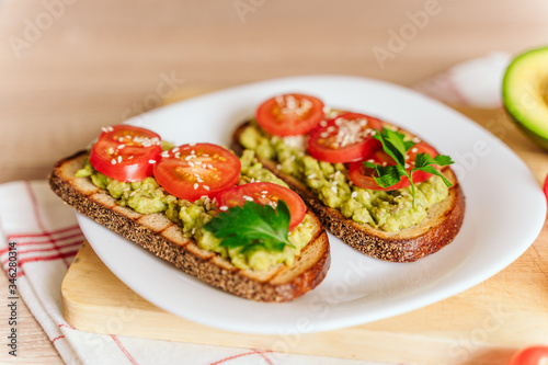 toasted bread with avocado paste and fresh tomato. Avocado mixed with lemon juice is spread on bread. health food concept, vegan, vegetarian