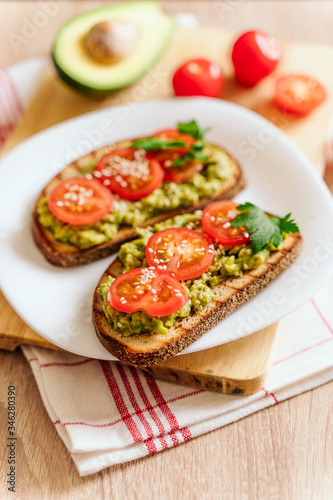 toasted bread with avocado paste and fresh tomato. Avocado mixed with lemon juice is spread on bread. health food concept, vegan, vegetarian