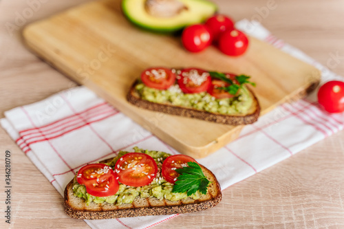 toasted bread with avocado paste and fresh tomato. Avocado mixed with lemon juice is spread on bread.  health food concept, vegan, vegetarian