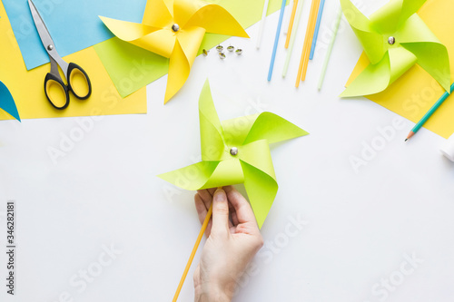 How to make paper green windmill toy with children at home. Step by step instructions. Hands making DIY summer project. Top view. Step 12. Enjoy ready toy.