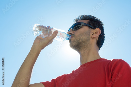 dark-haired boy with sunglasses drinking mineral water