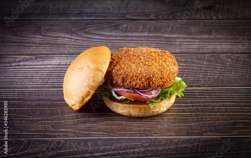 Chicken burger with lettuce, tomato, purpple onion and handmade mayo on the wood table. Delicious. photo