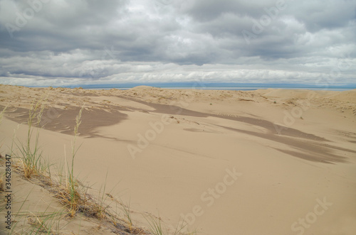 Dramatic clouds over the sand dunes at morning. Barkhan Mongol-Els sands on the coast of saltwater lake Dorgon. Nature and travel. Mongolia  Gobi Desert  Govi-Altai