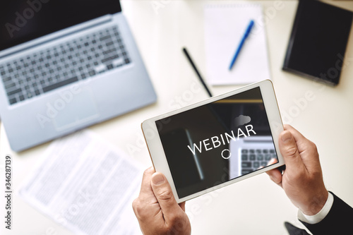 Webinar concept, online training. man holds in his hands a tablet with the inscription Webinar