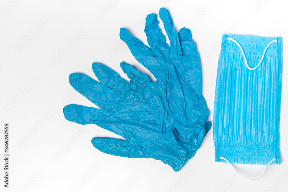 Blue medical face mask and a pair of gloves isolated on white background. Copy space, top view Blue medical face mask and a pair of gloves isolated on white background. Copy space, top view