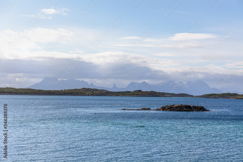 Norwegian fjord and mountains surrounded by clouds, ideal fjord reflection in clear water. selective focus.