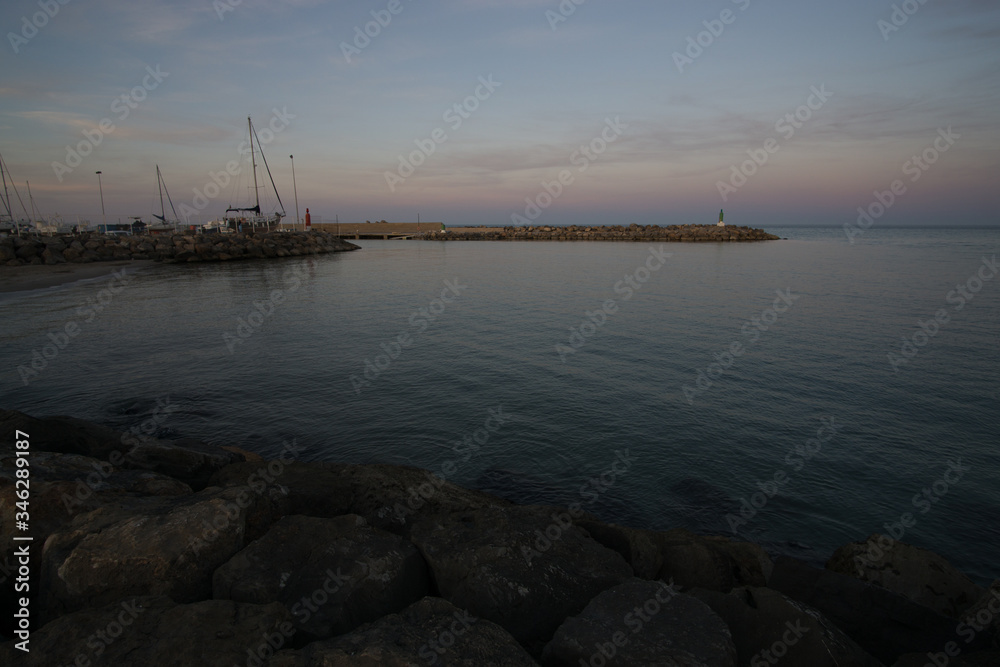 Fotografía Tomada en el espigón del Puerto de Sagunto. Se muestra un paisaje marinero en el cual aparece el espigón el mar y parte de puerto marítimo. 