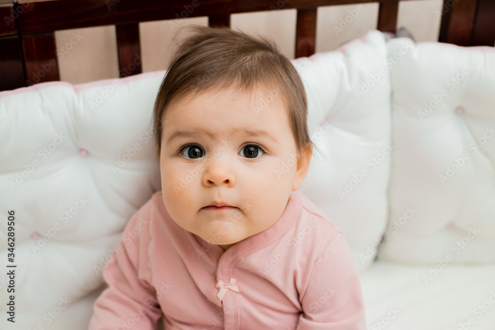 Portrait of a toddler girl sitting at home in a cot in her pajamas Portrait of a toddler girl sitting at home in a cot in her pajamas