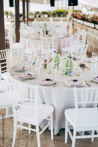 Wedding dinner table reception. Round banquet table with white tablecloth and white Chiavari chairs. Wedding under the tent.  © Nadtochiy