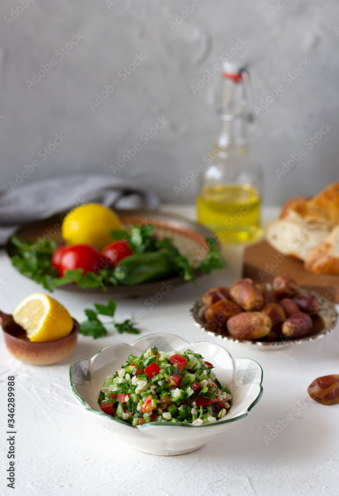 Iftar, evening meal during month of Ramadan. Tabbouleh salad, dates, fresh vegetables, bread on the table Iftar, evening meal during month of Ramadan. Tabbouleh salad, dates, fresh vegetables, bread on the table