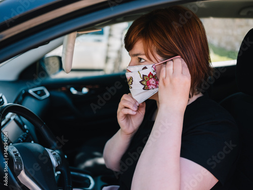 Frau mit Mundschutz im Auto auf dem Weg zur Arbeit photo