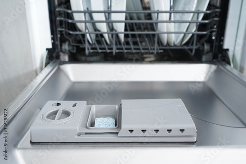 Full dishwasher, focus on dishwasher detergent tablet. Close-up.