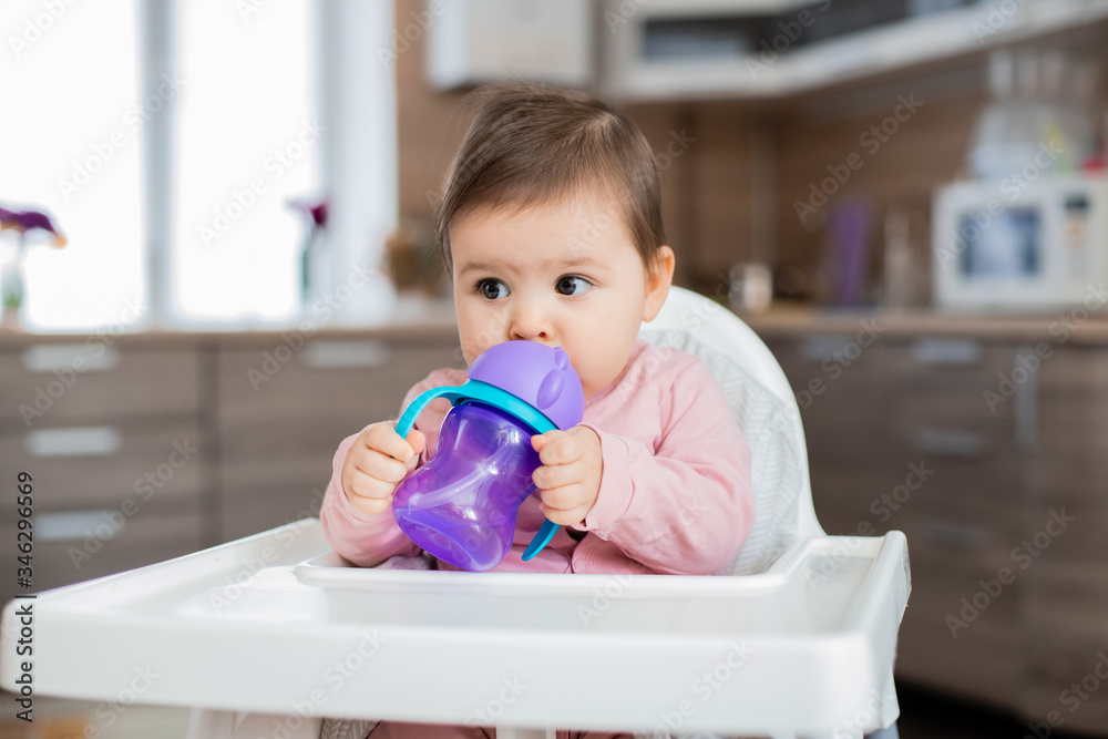 Toddler girl sits in a child's chair in the kitchen Toddler girl sits in a child's chair in the kitchen