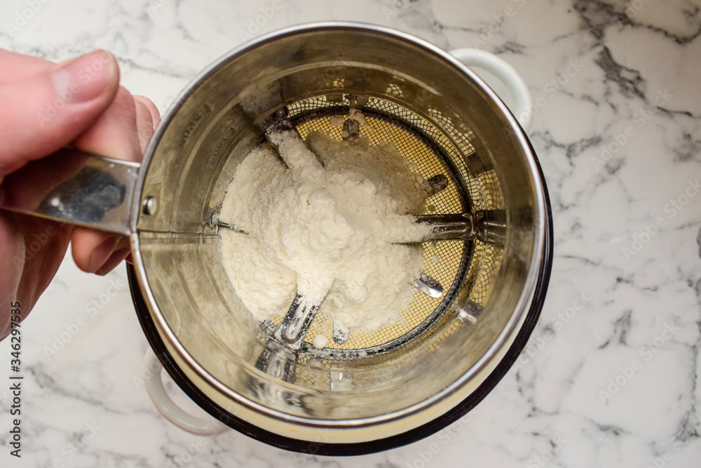 Fototapeta premium Flour sifting through a sieve
