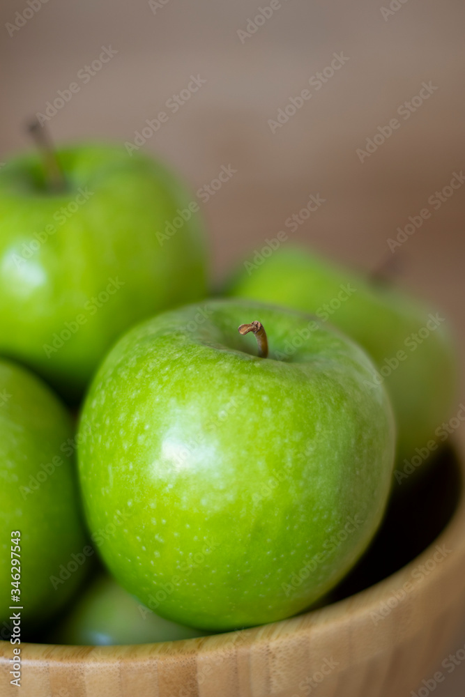 Green apples in a wooden bowl close-up. One green Apple close-up. Green apples in a wooden bowl close-up. One green Apple close-up.