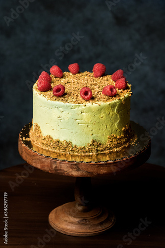 Beautiful yellow cake.Decorated with raspberries.Handmade work.Wooden high stand