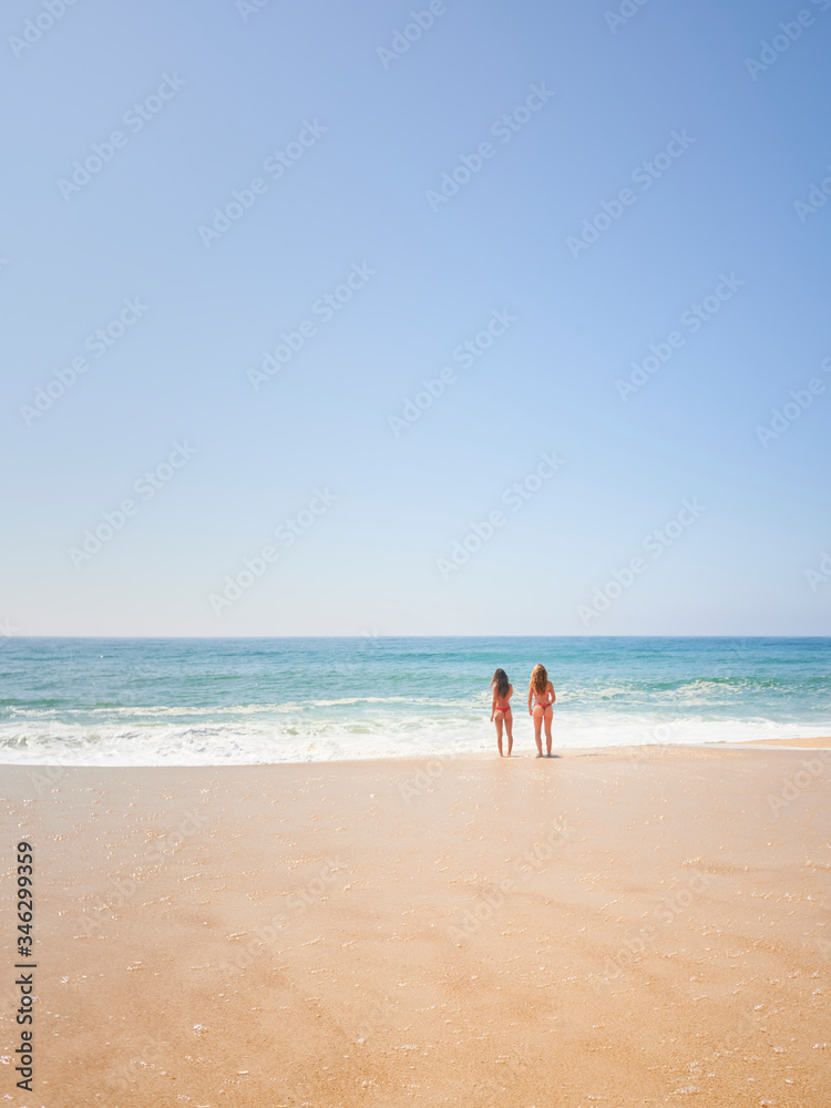 Two girls friends on relaxing on the beach at Norte beachm Nazaré