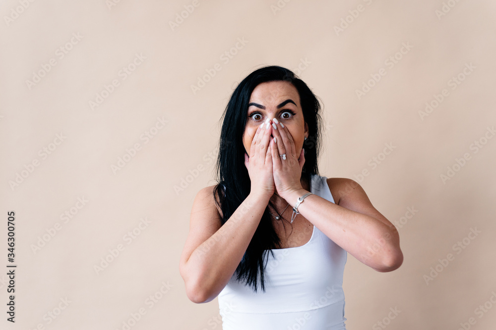 Keep silence. Scared woman covering mouth with hands while posing to camera on yellow studio background. Shocked girl Keep silence. Scared woman covering mouth with hands while posing to camera on yellow studio background. Shocked girl