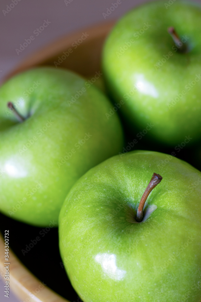 Three green apples in a wooden bowl close up Three green apples in a wooden bowl close up