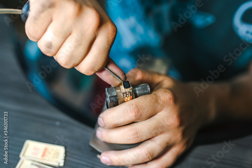 Master of jewelry while working on gold ring.