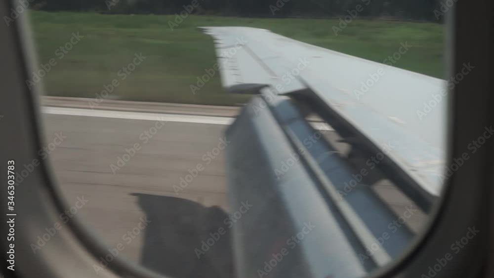 Jet plane landing at airport. View from window of the plane to the wing