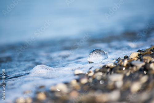 a child's hand holds a glass ball against the background of the sea