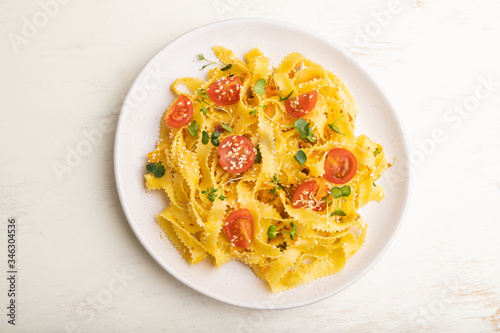 Reginelle pasta with tomato, eggs, sesame and microgreen sprouts on a white wooden background. Top view, close up.