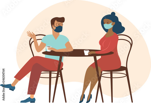 Cute couple wearing protective medical masks sitting at table, drinking tea or coffee and talking. New cafe visiting regulations during coronavirus COVID-19 outbreak.
