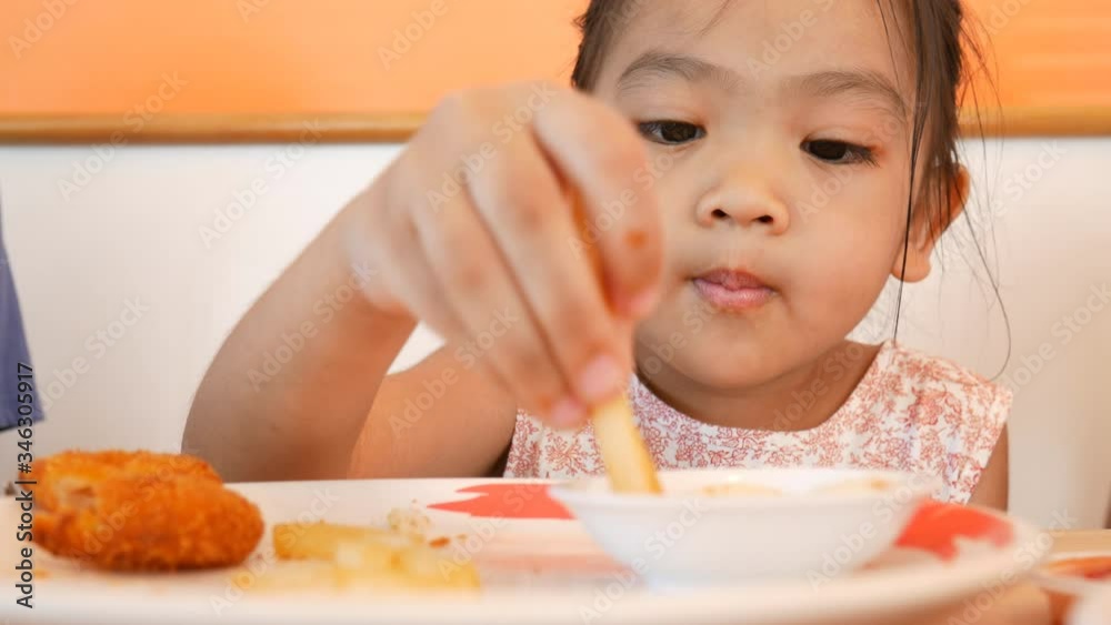 The Asian little kid feels delicious with French fries and snacks. The Asian little kid feels delicious with French fries and snacks.