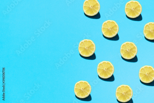 Summer abstract trendy fresh concept. Lemon pattern on bright light blue background, copy space. Minimal flat lay food texture.