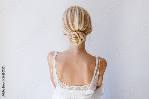 Collected blonde hair in a hairstyle on a light background.