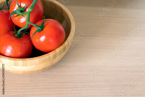 red tomatoes from a wooden bowl on the table top view