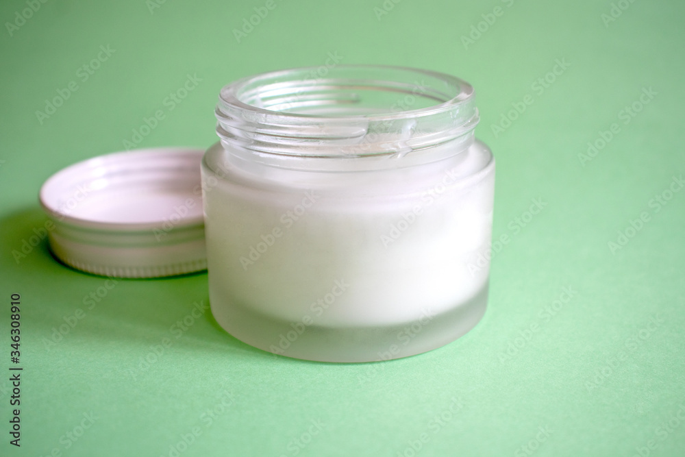 Glass container for cosmetics isolated on a green background. Free of plastic. Beauty concept. Glass container for cosmetics isolated on a green background. Free of plastic. Beauty concept.