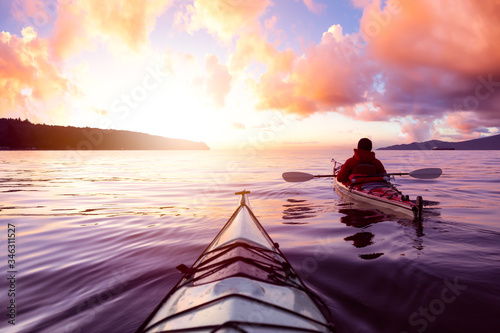Adventurous Man Sea Kayaking in the Ocean during a colorful Sunset. Cloudy Sky Composite. Taken in Jericho  Vancouver  British Columbia  Canada.