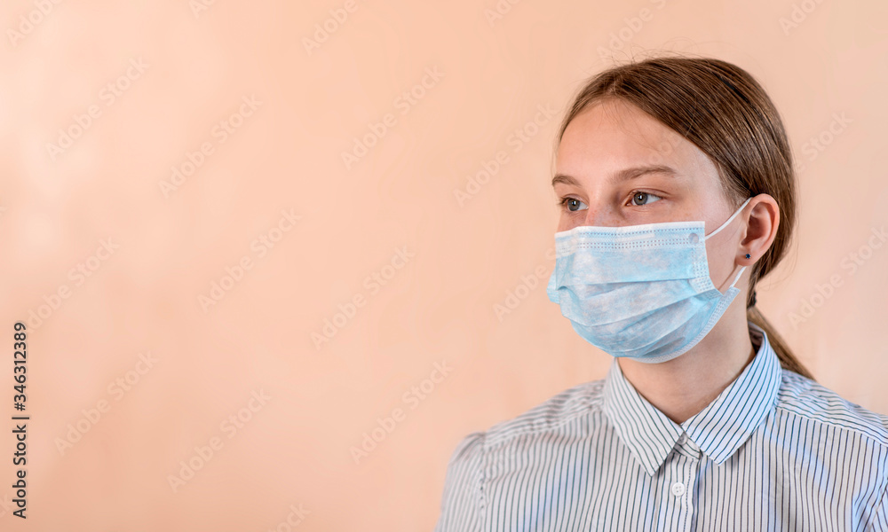 teenager girl of 12-15 years old, in a protective medical mask covers her face, free space for copy text. Flu infection is a disease and pandemic. Beige background. teenager girl of 12-15 years old, in a protective medical mask covers her face, free space for copy text. Flu infection is a disease and pandemic. Beige background.