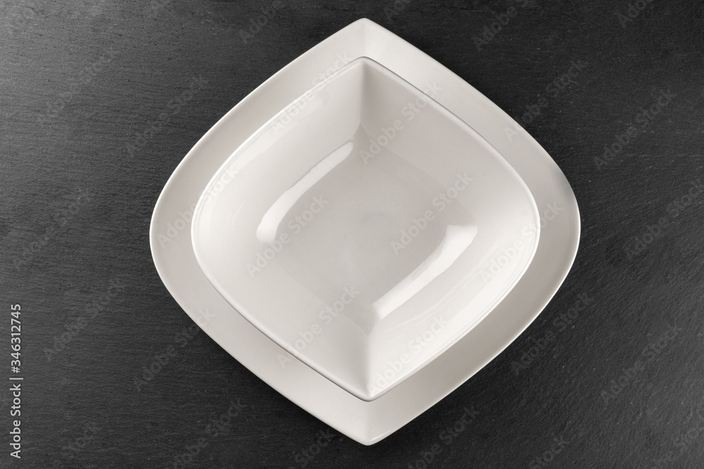 White plate on stone. Empty round dish isolated on dark. Food dinner background. Restaurant kitchen minimalistic concept. White plate on stone. Empty round dish isolated on dark. Food dinner background. Restaurant kitchen minimalistic concept.