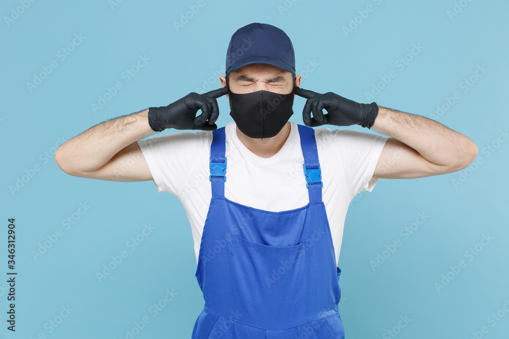 Delivery man in cap t-shirt coveralls uniform sterile face mask gloves isolated on blue background studio. Guy employee courier Service quarantine pandemic coronavirus virus covid-19 2019-ncov concept Delivery man in cap t-shirt coveralls uniform sterile face mask gloves isolated on blue background studio. Guy employee courier Service quarantine pandemic coronavirus virus covid-19 2019-ncov concept