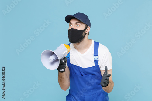 Delivery man in cap t-shirt uniform mask gloves isolated on blue background studio Guy fun employee courier scream in megaphone Service quarantine pandemic coronavirus virus covid-19 2019-ncov concept
