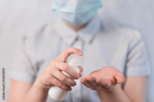 Close-up, children's hands apply antiseptic in palm of your hand, disinfection safety, prevention of influenza and covid-19 disease and infection in pandemic. In medical mask on white background.