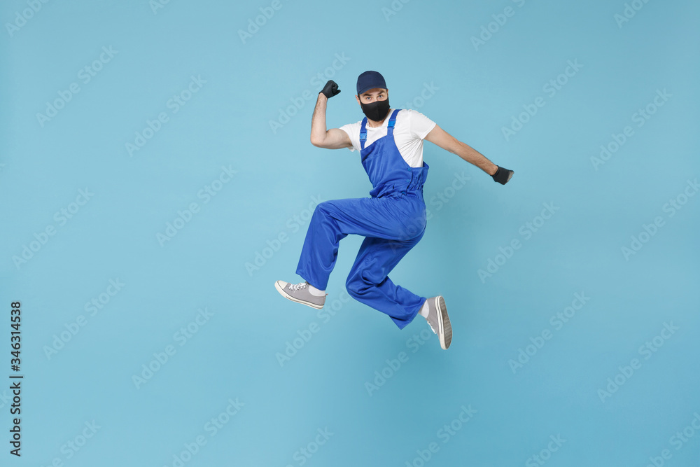 Fun jumping delivery man in cap t-shirt uniform sterile face mask glove isolated on blue background studio Guy employee courier Service quarantine pandemic coronavirus virus covid-19 2019-ncov concept Fun jumping delivery man in cap t-shirt uniform sterile face mask glove isolated on blue background studio Guy employee courier Service quarantine pandemic coronavirus virus covid-19 2019-ncov concept