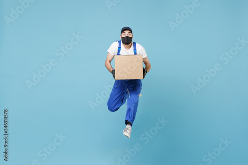 Fun jumping delivery man in cap t-shirt uniform sterile face mask glove isolated on blue background studio Guy employee courier Service quarantine pandemic coronavirus virus covid-19 2019-ncov concept