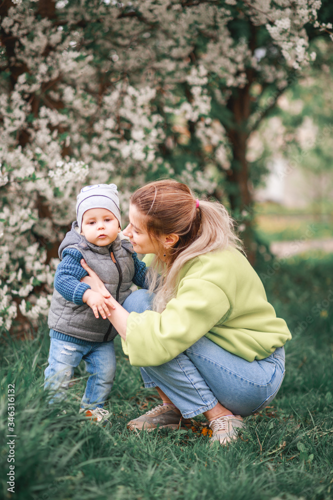 happy mother and son play against the background of a flowering tree. Spring, mother's day. happy mother and son play against the background of a flowering tree. Spring, mother's day.