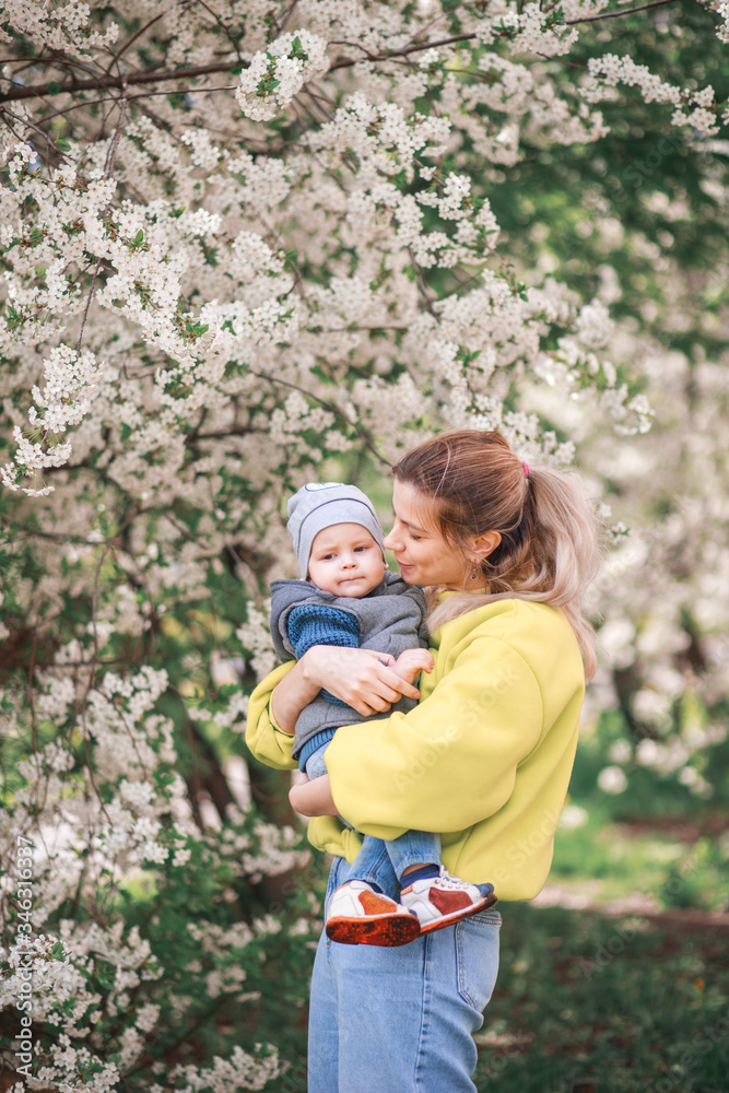 happy mother and son play against the background of a flowering tree. Spring, mother's day. happy mother and son play against the background of a flowering tree. Spring, mother's day.